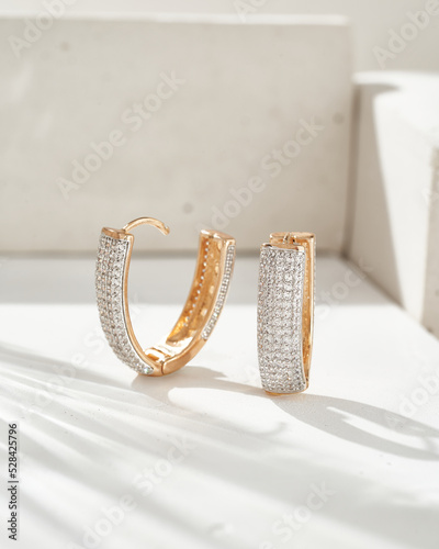 Golden earrings with white crystals and diamonds. Beautiful earrings on white background. Women accessories. Fashionable jewelry. photo