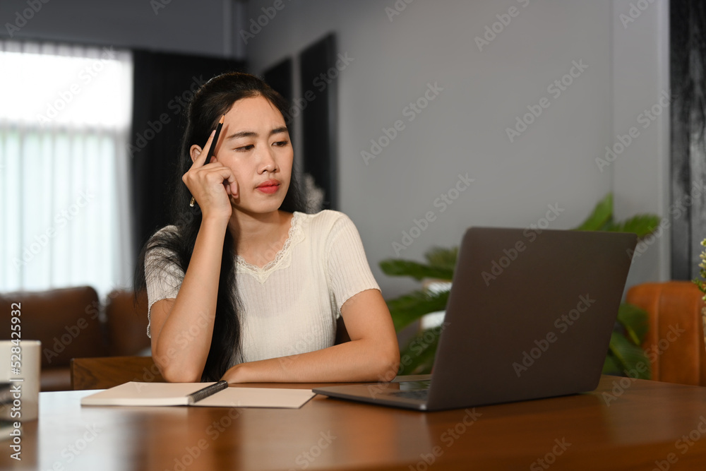 Concentred young woman looking at computer tablet while studying online on web virtual class at home. E-learning education concept Concentred young woman looking at computer tablet while studying online on web virtual class at home. E-learning education concept