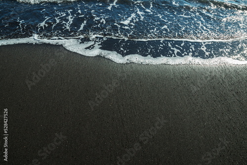 Ocean foam covering wonderful black sand beach of Tenerife island.