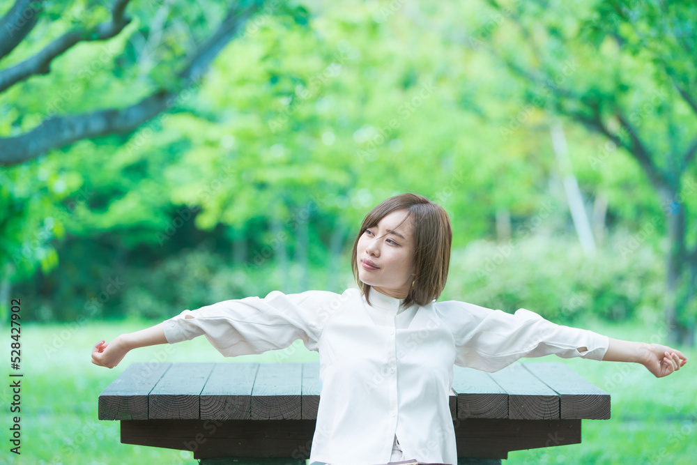 Naklejka premium 緑あふれる公園でくつろぐ女性