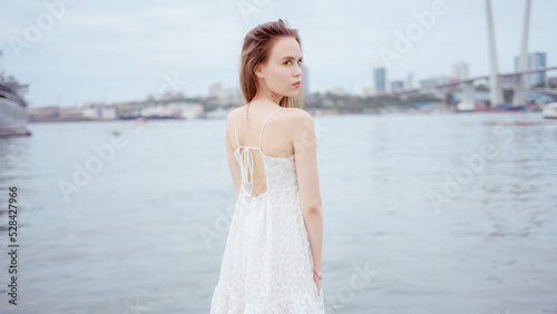 City portrait of beautiful young woman in white dress.