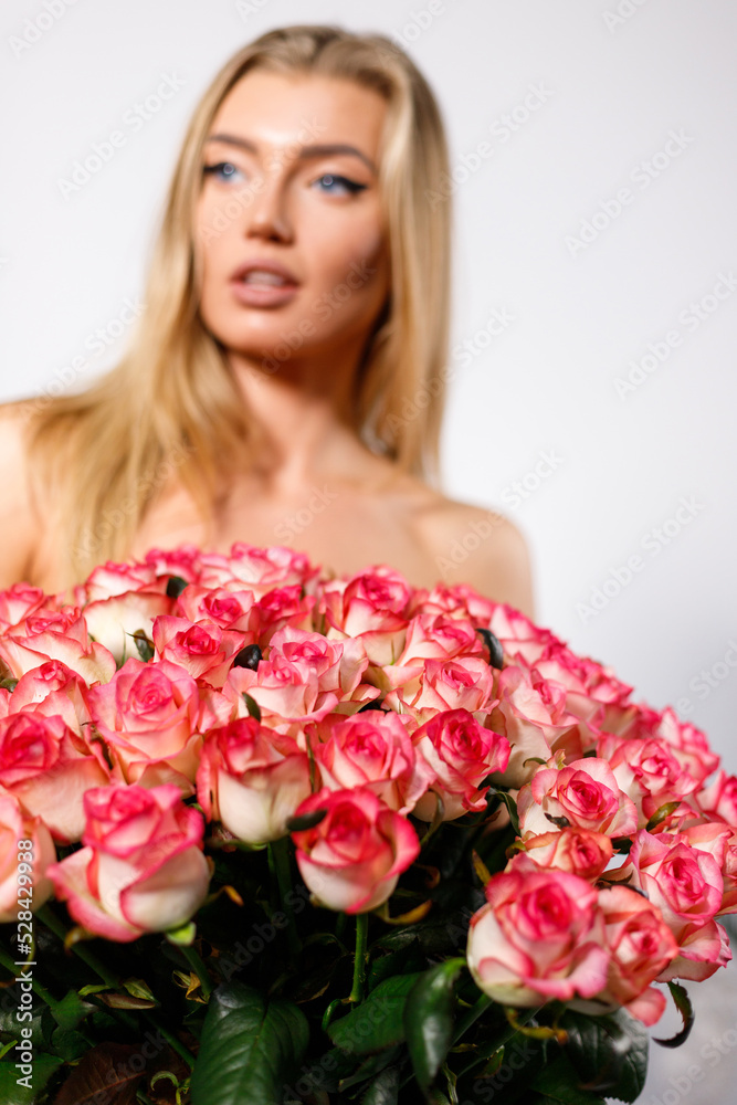 Beautiful large bouquet of pink roses on background of woman with bare shoulders.