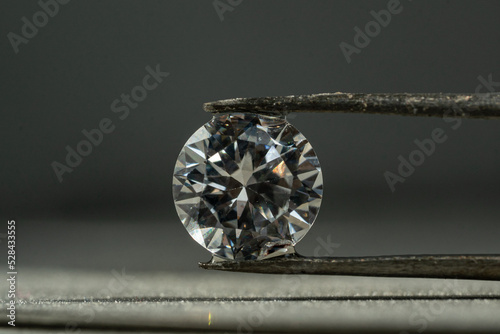 close up photo of round Diamond in Tweezers on polishing surface