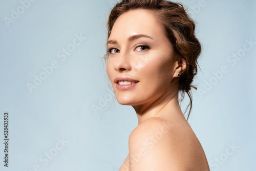 Pretty female with healthy glowing moisturized skin, bare shoulders looking at camera. Studio portrait of woman pleased with skincare antiaging treatment procedure. Natural organic cosmetics ad