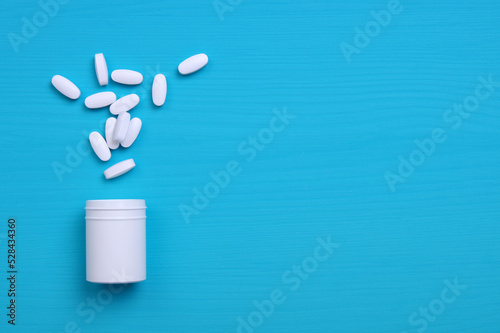 Pills and white bottle on blue background.