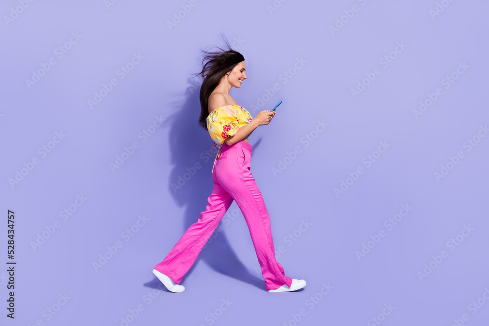 Full size profile photo of gorgeous person hold use telephone walking isolated on violet color background Full size profile photo of gorgeous person hold use telephone walking isolated on violet color background