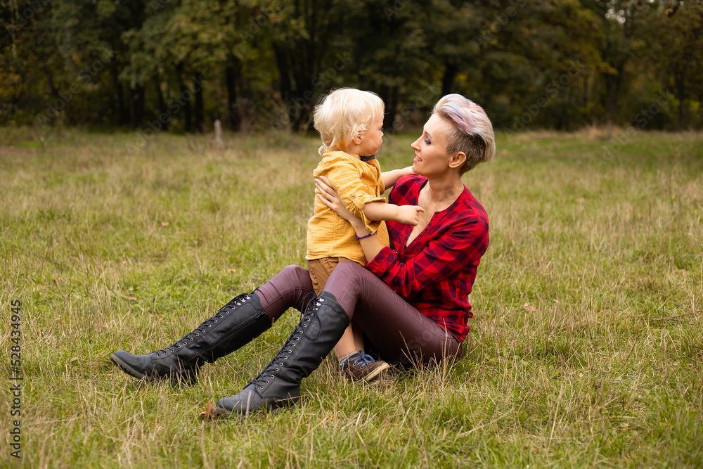 Fototapeta premium Mother with her little son sitting in autumn or summer forest