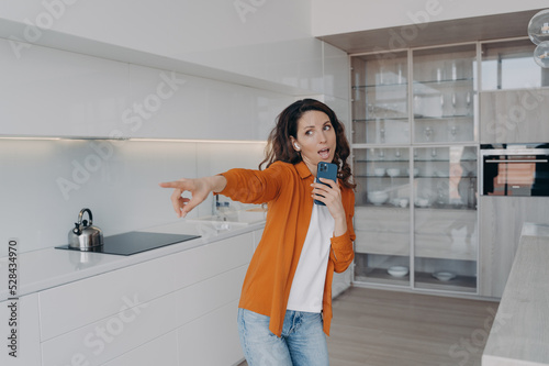 Energetic girl listens to music, singing using smartphone as mic at home. Musical mobile apps ad