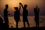 Photo of excited dreamy hippie people company dancing together enjoying sunset outside seaside beach