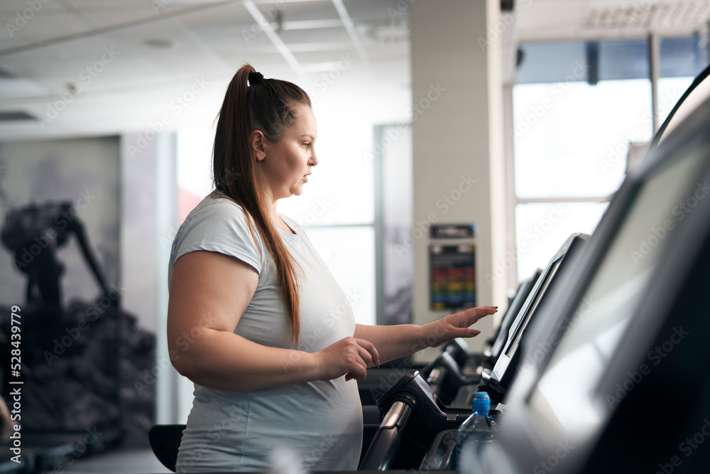 Plus size caucasian woman running on treadmill at gym Plus size caucasian woman running on treadmill at gym