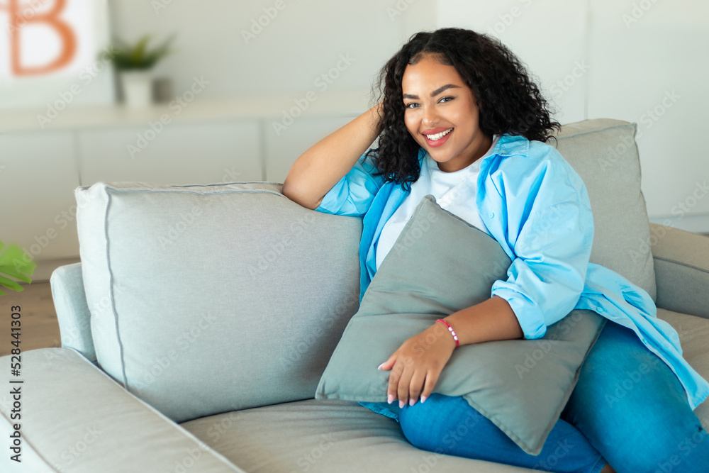 Happy African American Woman Sitting On Sofa At Home Happy African American Woman Sitting On Sofa At Home