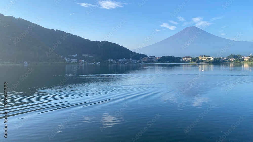 The waves that spread on the surface of the lake after a boat pass by, with beautiful clear silhouette of the Mt. Fuji from Kawaguchiko, lakeshore year 2022 August 27th, Japan
