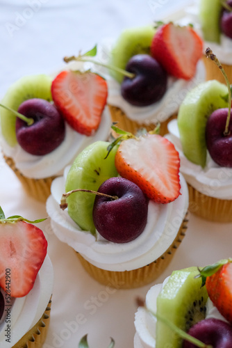 Butter cupcakes topped with strawberries, oranges and blueberries. Homemade bakery concept.. photo