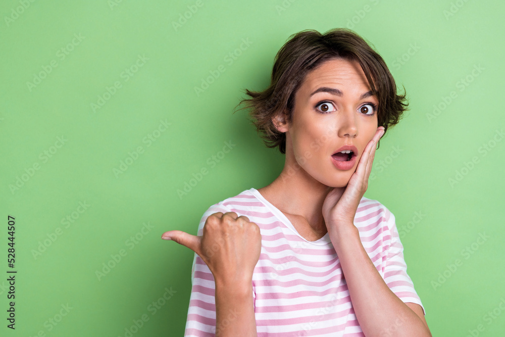 Photo of impressed bob hairdo young lady indicate promo wear white striped t-shirt isolated on green color background Photo of impressed bob hairdo young lady indicate promo wear white striped t-shirt isolated on green color background