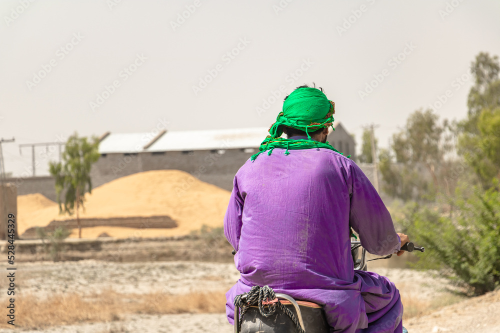 pakistani villager is traveling on a bike on a highway pakistani villager is traveling on a bike on a highway