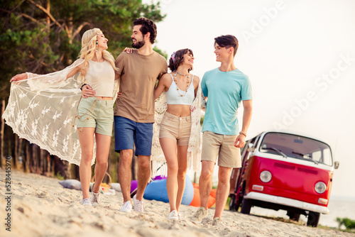 Photo of carefree adorable hippie people company smiling enjoying time together riding retro van outside seaside beach