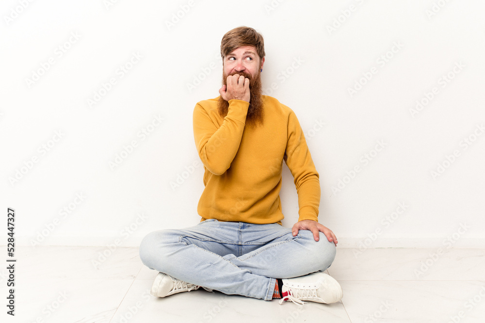 Young caucasian man sitting on the floor isolated on white background relaxed thinking about something looking at a copy space. Young caucasian man sitting on the floor isolated on white background relaxed thinking about something looking at a copy space.