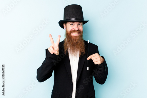 Young magician man isolated on blue background showing number two with fingers.