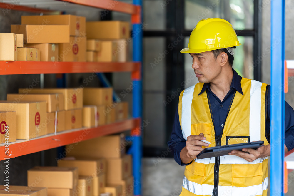 Portrait of middle aged asian warehouse worker standing in large warehouse distribution center. Portrait of middle aged asian warehouse worker standing in large warehouse distribution center.