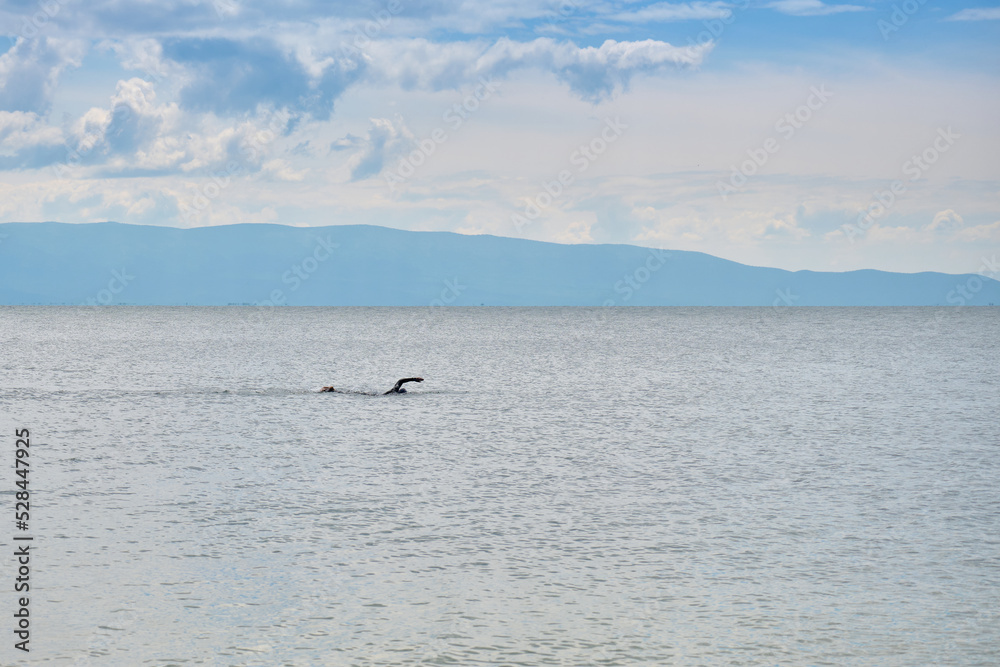 A man in a wetsuit trains in open water on Lake Baikal in the Chivyrkuysky Bay of the Republic of Buryatia.