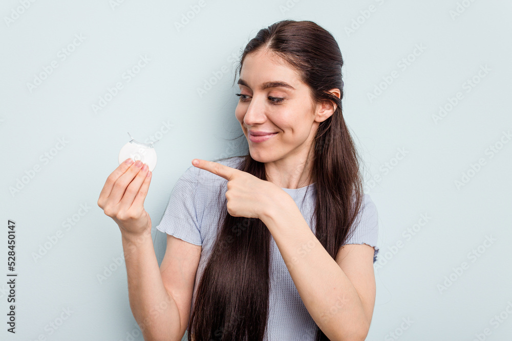Young caucasian woman getting a dental whitening isolated on blue background Young caucasian woman getting a dental whitening isolated on blue background