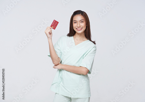 Happy asian woman patient showing credit card isolated on white background. Insurance allowance and charge indemnification concept. photo