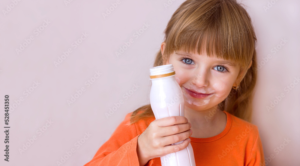 Portrait of a little beautiful girl with emotions on her face, her mouth stained with milk, holding a plastic bottle with a milk drink, yogurt or kefir, selective focus Portrait of a little beautiful girl with emotions on her face, her mouth stained with milk, holding a plastic bottle with a milk drink, yogurt or kefir, selective focus