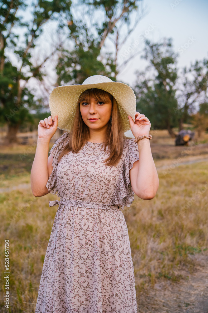 A young woman in a hat in a clearing. A walk in the park or forest. Outdoor recreation. The atmosphere of freedom and tranquility.