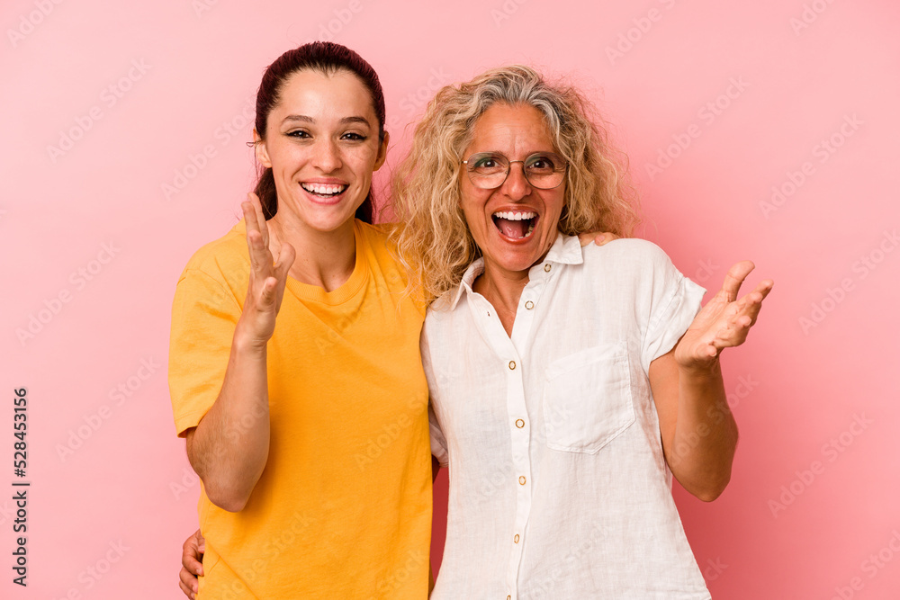Caucasian mom and daughter isolated on pink background receiving a pleasant surprise, excited and raising hands. Caucasian mom and daughter isolated on pink background receiving a pleasant surprise, excited and raising hands.