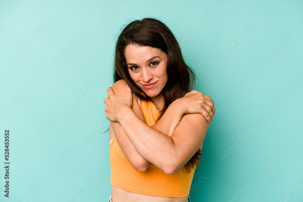 Young caucasian woman isolated on blue background hugs, smiling carefree and happy. Young caucasian woman isolated on blue background hugs, smiling carefree and happy.