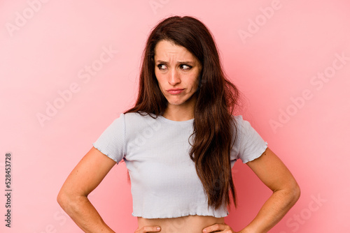 Young caucasian woman isolated on pink background confused, feels doubtful and unsure.