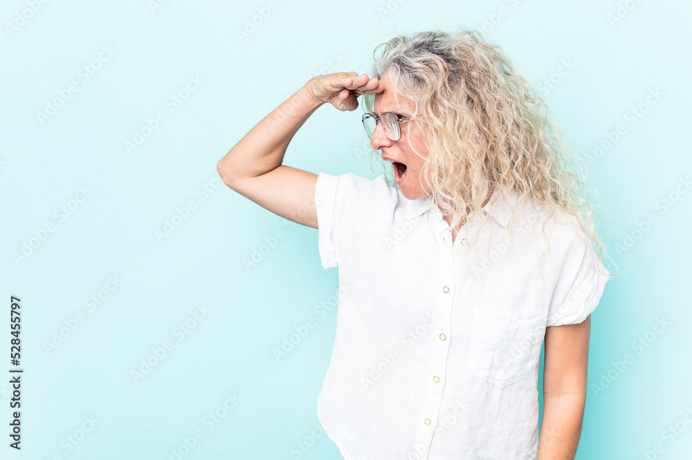 Middle age caucasian woman isolated on blue background looking far away keeping hand on forehead. Middle age caucasian woman isolated on blue background looking far away keeping hand on forehead.