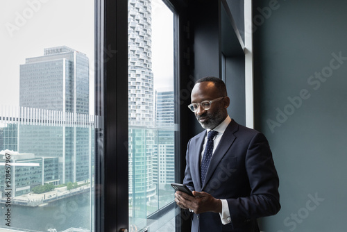 African American businessman using smartphone with view of city skyline photo