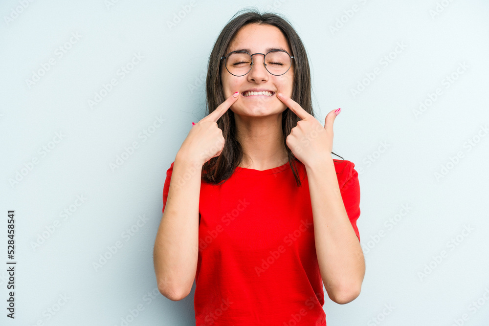 Young caucasian woman isolated on blue background smiles, pointing fingers at mouth. Young caucasian woman isolated on blue background smiles, pointing fingers at mouth.