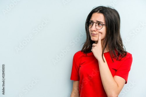Young caucasian woman isolated on blue background looking sideways with doubtful and skeptical expression. © Asier