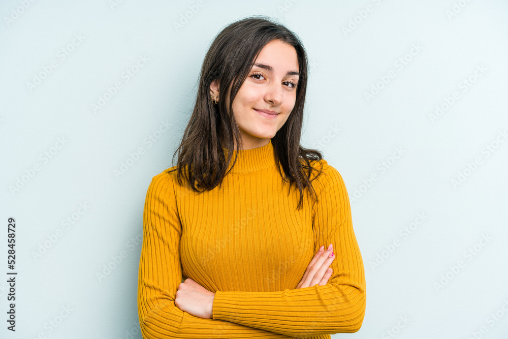 Young caucasian woman isolated on blue background who feels confident, crossing arms with determination. Young caucasian woman isolated on blue background who feels confident, crossing arms with determination.