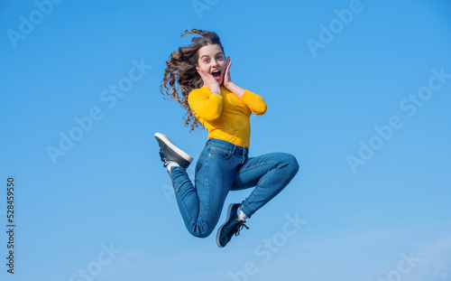 amazed teen girl jump high on sky background