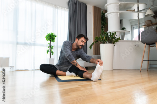 Young man rehabilitation exercise at home after car crash accident. Recovery workout of young guy with yoga training poses for stretching the muscles. Physical therapy exercising