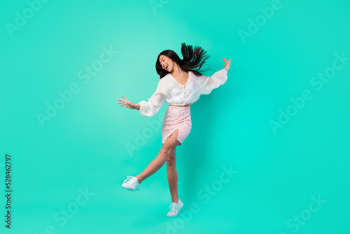 Full body photo of pretty positive malaysian person have fun dancing clubbing isolated on shine emerald color background