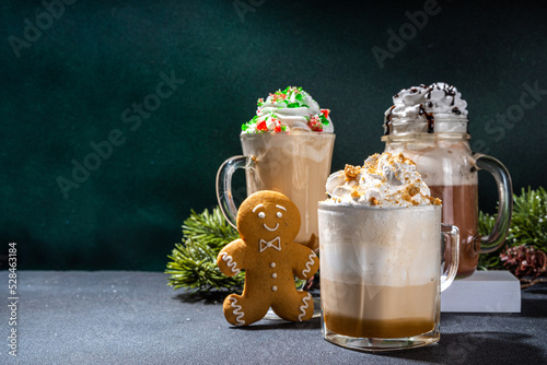 Autumn winter coffee latte set, Autumn winter coffee drink assortment with various topping - gingerbread caramel, mocha chocolate, candy cane peppermint latte in different cups, over dark background