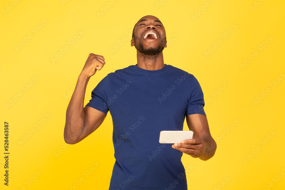 Black Guy Using Cellphone Gesturing Yes In Joy, Yellow Background Black Guy Using Cellphone Gesturing Yes In Joy, Yellow Background