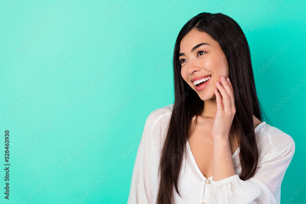 Portrait of adorable cheerful malaysian lady hand touch cheek look interested empty space isolated on turquoise color background Portrait of adorable cheerful malaysian lady hand touch cheek look interested empty space isolated on turquoise color background