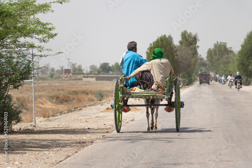 two villagers are traveling on a donkey buggy 