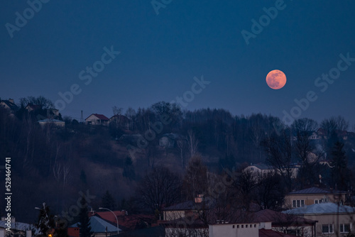Red moon is rising above a hill. Dark blue colors and spectacular full moon