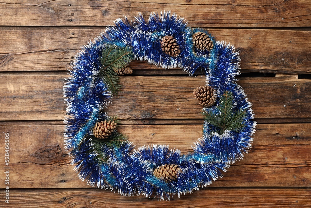 Frame of bright tinsel, fir tree branches and pine cones on wooden background, top view with space for text. Christmas decor Frame of bright tinsel, fir tree branches and pine cones on wooden background, top view with space for text. Christmas decor