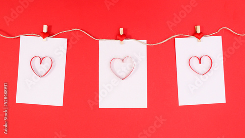 Romantic papers with heart hanged on rope on red background. Flat lay