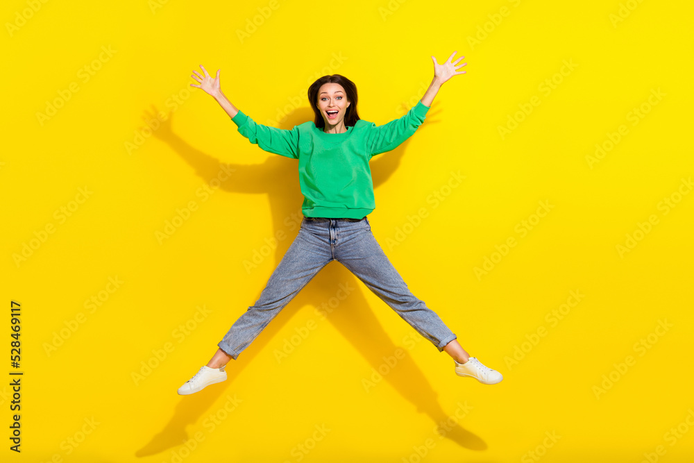 Full size photo of overjoyed pretty girl jumping raise hands make star figure isolated on yellow color background