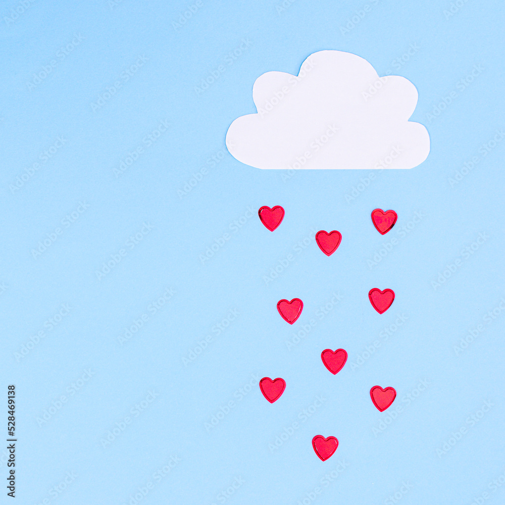 Creative concept of cloud with raining hearts on pastel blue background. Flat lay