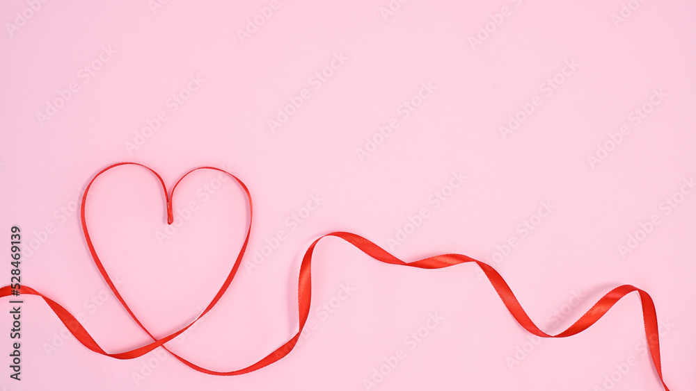 Heart made with red ribbon on pastel pink bacgkround. Flat lay VAlentine's day concept