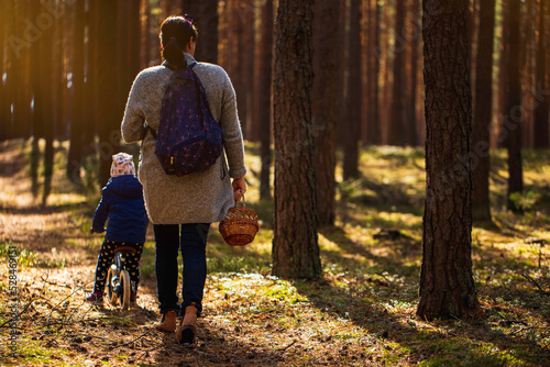 Obraz na płótnie Woman with her child are walking in autumn forest ang picking up the mushrooms to wooden basket. w salonie